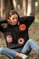 Sweater negro de lana con cuello redondo y apliques de flores de crochet multicolores.