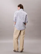 Pantalón parachute color beige de nailon arrugado, corte holgado, cintura elástica con cordón interior, puños con cordón y cremallera, cierre mediante botón y cremallera, diseño de bolsillo superpuesto y bordado de Calvin Klein en la cadera.