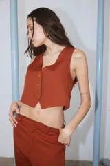 Chaleco color ladrillo de tela sastrera con forrería de poplín de algodón a tono, escote en V y cierre frontal con botones.