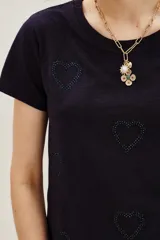 Remera de algodón color azul marino con cuello redondo y mangas cortas. Presenta un estampado de corazones formados por pequeñas aplicaciones brillantes distribuidas por toda la prenda.