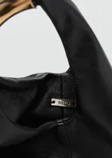 Bolso de mano pequeño con diseño estructurado y minimalista en color negro. Presenta un asa superior rígida de metal dorado y cuerpo de material sintético con acabado texturizado.