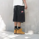 Bermuda baggy de denim negro con costuras en contraste blancas, bolsillos traseros grandes y un parche bordado en forma de estrella con la inscripción 'Venefo'.