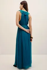 Vestido largo color verde turquesa, confeccionado en gasa con forrería a tono. Posee escote en V profundo con volados, sin mangas, y corte en la cintura con lazo ajustable.