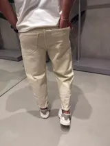 Jean de corte slouchy en color beige, confeccionado en denim de algodón. Presenta un diseño de tiro medio con ajuste holgado en la cadera y muslos, estrechándose hacia los tobillos.