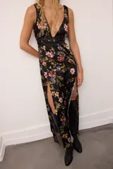 Vestido largo de gasa estampada con flores, con escote en V profundo y detalles de cuero ovino en los bordes y cintura. Presenta dos tajos delanteros y tiras ajustables en la espalda.