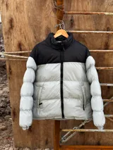 Campera puffer gris con sección superior negra y cierre frontal.
