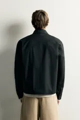Sobrecamisa negra de corte relaxed fit, confeccionada en tejido de algodón con elasticidad. Cuenta con cuello solapa, manga larga con puño abotonado, bolsillos de vivo en la cadera y cierre frontal de botonadura.