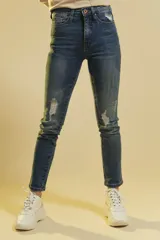 Pantalón de jean corte regular con efecto desgastado y roturas localizadas en las rodillas y bolsillo delantero. Presenta un tono azul medio con costuras a tono y cierre frontal con botón metálico.