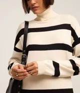 Vestido midi de punto con cuello alto y mangas largas. Diseño recto con rayas horizontales negras sobre fondo crudo y aberturas laterales.