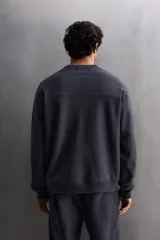 Sudadera negra de entrenamiento relaxed fit confeccionada en tejido de algodón con interior rizo, cuello redondo, manga larga y acabados en rib.