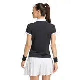 Remera polo de mujer Adidas de manga corta, color negro con detalles en blanco en el cuello, la botonera, los bordes de las mangas y las clásicas tres tiras en los hombros. Incluye el logo del trifolio bordado en el pecho.