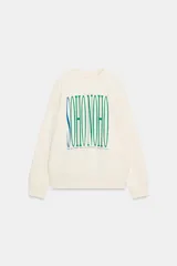 Sudadera de tejido mezcla de algodón color crema, con cuello redondo y manga larga. Presenta un estampado central con el texto "SOHO NOHO" en tipografía alargada, con las letras alternando entre azul y verde.