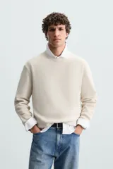 Sweater de punto color beige con textura tipo waffle, cuello redondo y mangas largas con acabado en rib.