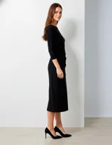 Vestido negro de seda fría, corte midi, con escote barco y mangas tres cuartos. Presenta frunces drapeados en la zona de la cintura y cadera.