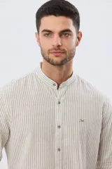 Camisa de lino a rayas verticales blancas y azules, de manga larga, con cuello mao y cierre frontal de botones.