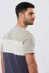 Remera de manga corta con diseño de bloques de color en tonos gris, blanco y azul marino. Cuenta con cuello redondo y una estampa tipográfica en el centro del pecho.