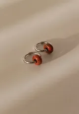 Aros argollas pequeñas de acero quirúrgico con dije de cuenta de piedra natural en tono rojizo.