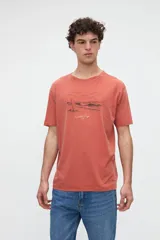 Remera de algodón lavado con textura suave, de manga corta y calce relaxed, color salmón con diseño estampado y bordado en el pecho.