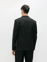 Ambo semi slim de color negro, compuesto por un saco estructurado de dos botones con solapa de muesca tradicional y un pantalón de corte contemporáneo.