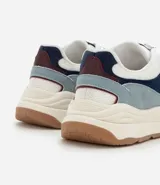 Championes estilo jogging con diseño de recortes contrastantes en tonos blanco, azul y gris. Presenta una parte superior de mesh respirable con sobreposiciones de poliuretano, forro suave y suela robusta de color crema con base marrón.