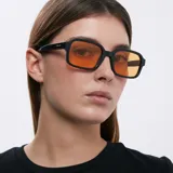 Lentes de sol cuadrados con ángulos redondeados, montura fina negra y lentes color naranja.