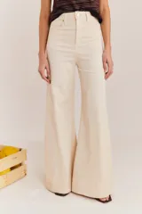 Jean de tiro alto y silueta acampanada color beige, confeccionado en algodón, con diseño ajustado en la cadera y corte amplio hacia los tobillos.
