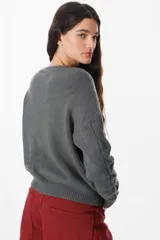Sweater de punto negro con diseño de trenzas verticales en el frente y cuello redondo. Presenta un corte holgado con puños y ruedo acanalados.