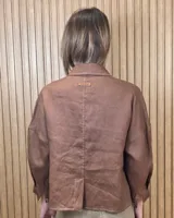 Sobrecamisa de lino color beige, con cuello camisero, cierre frontal de botones carey, mangas largas y bolsillos frontales con solapa.