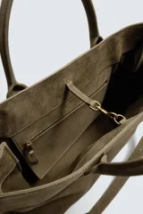 Bolso tipo bandolera de piel con acabado abatanado, diseño rectangular con doble asa de mano y detalle de llavero colgante. Cuenta con compartimento principal con cierre de mosquetón y bolsillo interior con cremallera.