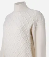 Suéter de manga larga confeccionado en tricot, con cuello alto y diseño de rombos bordados en relieve. Presenta puños y cintura ajustados en tejido acanalado.