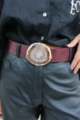 Cinto de cuero azul con hebilla circular de piedra ágata con borde dorado.