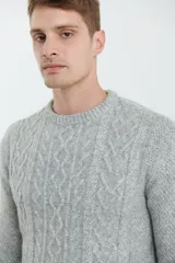 Sweater de tejido de punto color beige claro, con diseño de trenzas (aranes) en el frente y mangas de punto liso. Tiene cuello redondo.