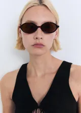 Top sin mangas de tejido de punto fino, con cuello en pico y detalle de lazo frontal en el escote. Presenta un diseño entallado con tirantes anchos.