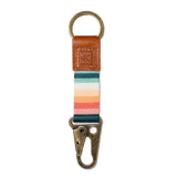 Llavero con tira de tela a rayas horizontales en tonos celeste, blanco, naranja, rosa y verde. Tiene un mosquetón metálico color bronce y una pieza de cuero marrón con el logo de la marca.