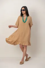 Vestido midi de lino color beige, con mangas cortas, cuello redondo, alforzas verticales en el pecho y detalle de volados en el ruedo.