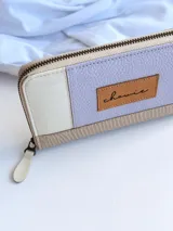 Billetera de cuero color lila, beige y blanco, con cierre metálico y monedero interno.
