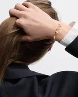 Dije colgante con forma de oso de peluche texturizado, color dorado, con detalle de cristal en una pata.