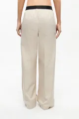 Pantalón de gabardina color beige, de corte recto, tiro medio-bajo, fit oversize y cintura elastizada con logo de la marca.