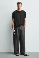 Sandalia plana negra con tiras anchas cruzadas sobre el empeine y una tira que separa el dedo gordo. Posee plantilla anatómica.