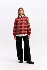 Sweater de punto con diseño de cuadros en tonos rojizos y anaranjados, de silueta relajada, cuello redondo y mangas largas con puños ajustados.