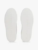 Zapatillas Tommy Hilfiger de diseño clásico y bajo, color blanco con detalles en rojo en la parte trasera del talón y en la lengüeta. Presentan cierre de cordones y el logo metálico distintivo de la marca en el lateral.