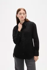 Camisa de jean negro con diseño de frunces verticales en el frente, cuello clásico, cierre frontal con botones y mangas largas con puños abotonados.
