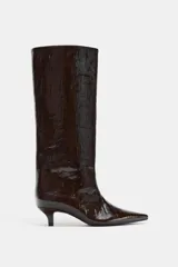 Bota de caña alta con acabado efecto craquelado en color marrón oscuro. Presenta un diseño de punta fina, tacón kitten y una estructura de calce fácil tipo pull-on.