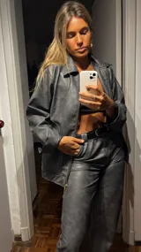 Campera de cuero sintético color gris oscuro, con cuello camisero, cierre frontal con cremallera dorada y bolsillos laterales.