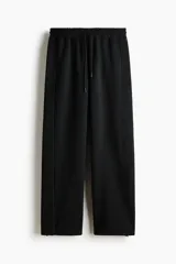 Pantalón de jogging deportivo de corte holgado, confeccionado en tejido técnico con tecnología de absorción de humedad. Presenta cintura elástica con cordón de ajuste, bolsillos laterales, ribetes verticales en las piernas y cordón elástico ajustable en los bajos.