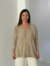 Sweater de punto color visón con estampado abstracto en color dorado brillante, cuello en V y mangas largas con diseño holgado.