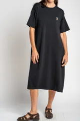 Vestido midi de punto color negro, con cuello redondo, mangas cortas y corte holgado. Presenta un pequeño bordado de un velero en el pecho.