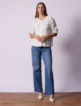 Blusa blanca de cuello redondo con apertura central y botones. Mangas 3/4 con detalle de bordado calado.