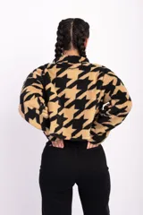 Campera corta de polar color beige con estampado de estrellas negras, cuello alto y cierre frontal.