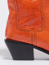 Botines cowboy de piel color naranja, con tacón en punta y tirador en la parte trasera. Forro de piel con plantilla con logo a contraste y suela con logo.
